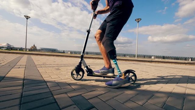 Scooter is being driven by a man with a bionic leg in slow motion
