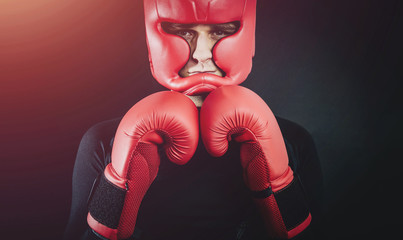 Boxer in boxing gloves and boxing helmet on a dark black background. Concept of sport and active...