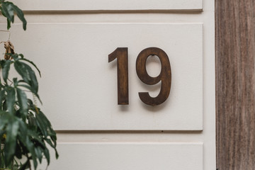 Steel plated numerals showing the house number nineteen. House number on a front house wall