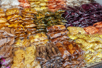 Obraz na płótnie Canvas Dried fruits and other sweet snacks are staked at a market booth, ready to be sold. A lot of such markets can be found along the streets in South East Asia.
