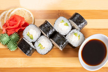 Sushi, maki, with curd cheese and avocado. On the plank.