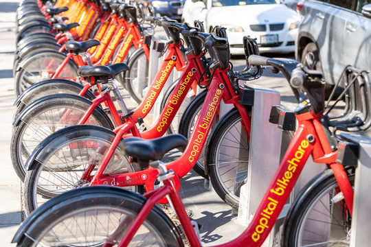 Washington DC, USA - April 5, 2018: Closeup of parking, bike rent, rental at docking station near road from capital bikeshare red bicycles row on sidewalk street in capital city