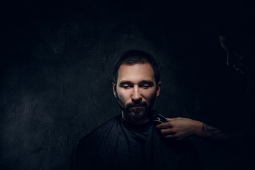 Portrait of pensive man with receive moustache and beard trimming procedure at barbershop.
