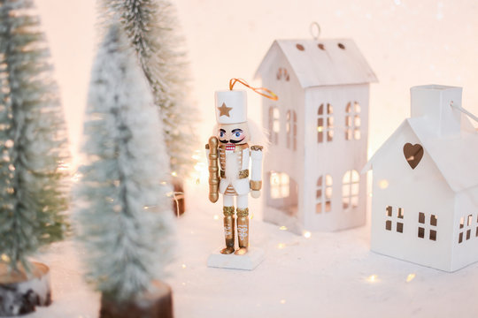 Christmas nutcracker toy soldier figurine ornament in white. Decoration for new year.  Nutcracker on the white sparkling background with conifers. Advent concept with bokeh lights.