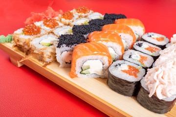 Assorted rolls and poppies. On the plank. On a red background.