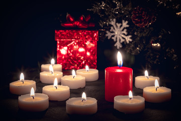 Christmas candles burning at night in front of a red gift box