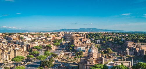 Fototapeta na wymiar Aerial panorama of Colosseum and Roman Forum in Rome city, Italy. Beautiful cityscape with old famous landmark ruins and historic center of Rome, view from above.