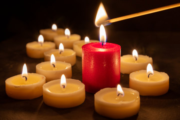Fototapeta na wymiar A match lights the fire of many candles