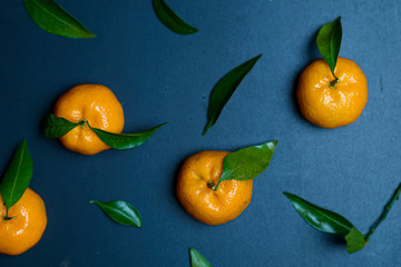 Ripe gorgeous tangerines with leaves isolated on a blue wooden background.