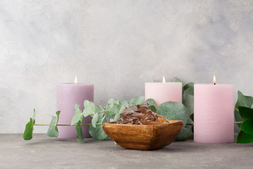 Spa concept. Three pink candles, Aloe Vera gel in wood plate and eucalyptus on grey background.