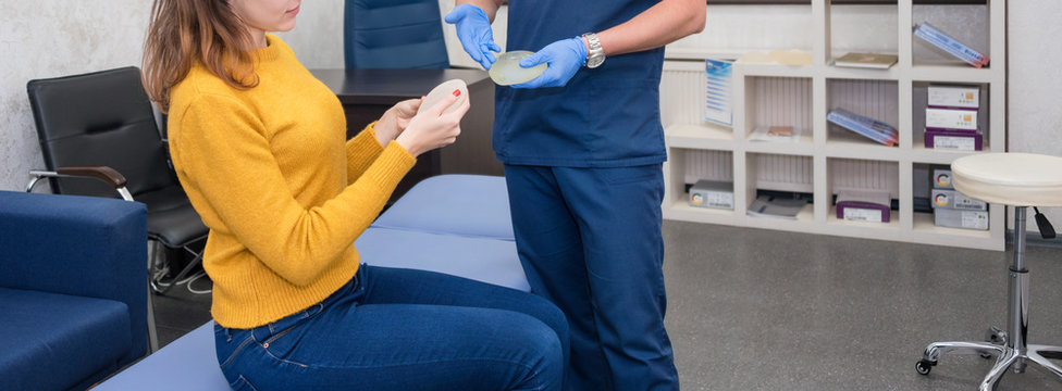 Woman planning to have a breast implant. Doctor showing breasts implants to female patient. Silicone implants for breast augmentation in clinic. Cosmetic surgery
