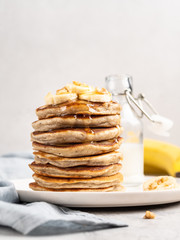 Breakfast banana pancakes stack decorated with chopped walnuts honey and banana slices