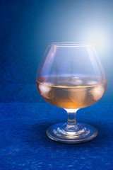 Glass of alcohol, whiskey with ice on a blue background.