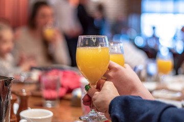 Enjoying mimosas at brunch - two hands clinking glasses - 302086437