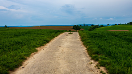 Dirt road in the field with diminishing perspective against blue sky in Neudenau, Germany.