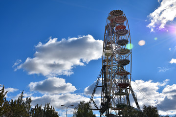 Colorful ferris wheel of fair illuminated by the morning sun with blue sky in the background