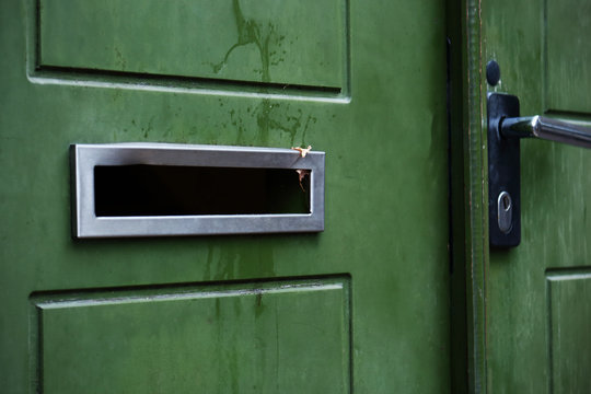 Green door with a hole for mail empty mail box