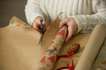  Woman cutting wrapping paper on the desk, holiday season gifting concept