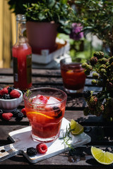 Cold refreshing lime, blackberry and raspberry lemonade with ice on wooden rustic table