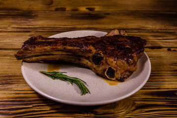 Plate with roasted ribeye steak on wooden table