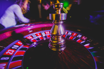 A close-up vibrant image of multicolored casino table with roulette in motion, with casino chips....