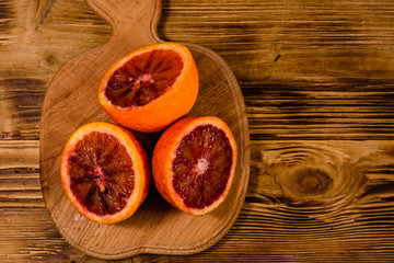 Cutting board with halved sicilian oranges on a wooden table. Top view