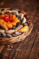 Mix of dried fruits in a small wicker basket on wooden table