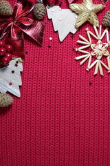 Christmas symbols tree, cone, star, berries, snowflake on a knitted red texture. New Year winter holiday background.