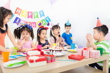 pretty asian children blow out candles on birthday Cake, asian children group meeting in celebration party, they sing happy birthday song and clasp hand, happiness activity