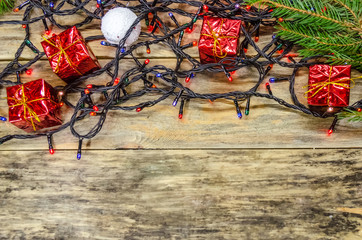Christmas background-Christmas lights, Christmas balls, small red gifts on wooden background. top...