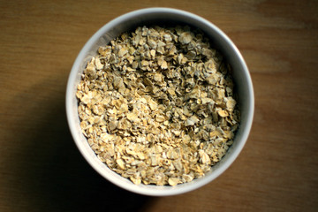 Bowl of raw oatmeal on wooden background