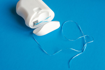 dental floss  on a blue background, the concept of care for the oral cavity, preventing tooth...