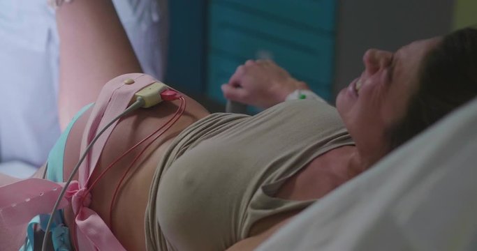 Authentic shot of an young pregnant woman is giving a birth to her future baby in a delivery room of a hospital.