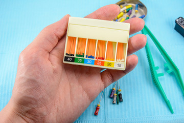 gutta-percha pins in a set of different sizes for root canal filling in the doctor’s hand,...
