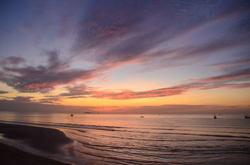 A tropical  orange  coloured stratocumulus cloud coastal sunrise seascape in a blue sky. Thailand.