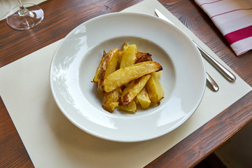 Roasted Potatoes Served On A Withe Plate On A Wooden Table.