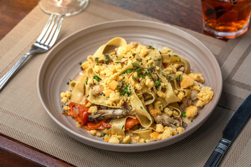 seafood pasta on a wooden table outside at a restaurant with a drinks at background