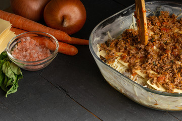 Italian Lasagna on a black background with ingredients. Cooking time. Recipe book and home menu.