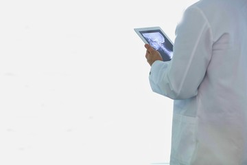 Doctor checking x-ray on digital tablet while standing at hospital