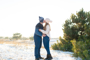 The guy with the girl kiss in the winter in the woods against the background of falling candy. Romantic winter atmosphere