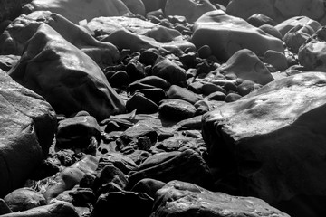 Black and white view of water stream with round rocks