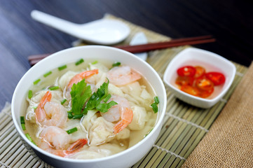 Homemade delicious Wonton soup with prawn and chilli in vinegar in dipping blow on wooden table