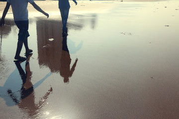 Reflection of two human walking on the beach