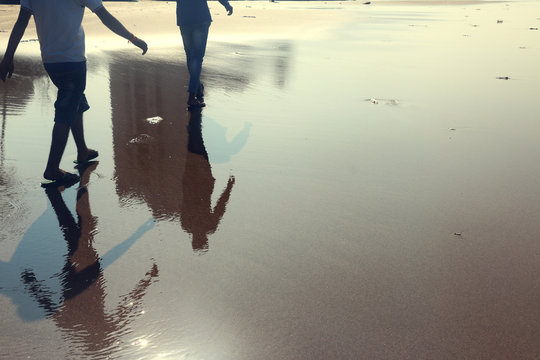 Reflection of two human walking on the beach