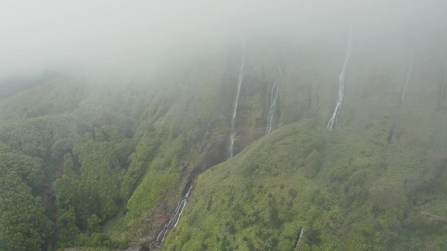 Steep slope with streams of water. Ferreiro waterfall disappears in a cloud on the top