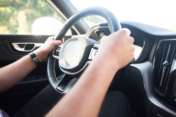 Man driving a car. Success in motion. Handsome young man driving a car. A man holds the steering wheel of a car.