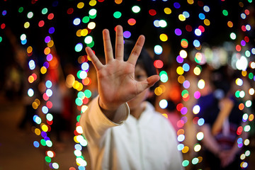 Young girl making stop sign on bokeh background, blur image