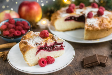 Delicious Christmas raspberry pie with berry filling and icing sugar and spices on a dark background.