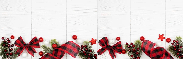 Rucksack Weihnachtsbanner aus Ornamenten, Ästen und rot-schwarz kariertem Büffel-Karoband. Ansicht von oben auf einem weißen Holzhintergrund. © Jenifoto