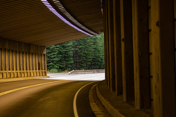 Curve tunnel for automobiles, exit at backgorund. Empty engineering construction with rhythm of...